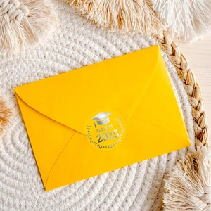 Close-up of Class of 2025 silver foil seal on a yellow envelope for graduation