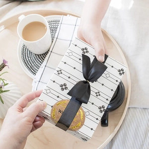 Boîte cadeau élégante avec ruban noir et motifs géométriques sur un plateau