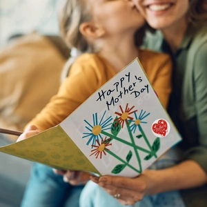 Detail of Happy Mother's Day sticker on card with floral design and warm bokeh background