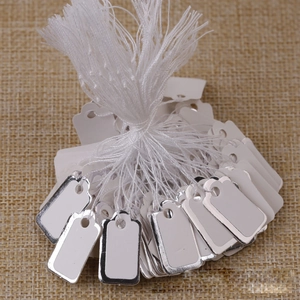 White jewelry price tags with elegant silver borders and strings on rustic linen background