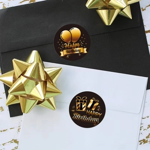 Close-up of black and gold Happy Birthday stickers on envelopes with festive decorations