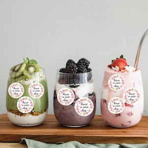 Pink floral 'Have a Nice Day' round stickers on colorful smoothies glass cups