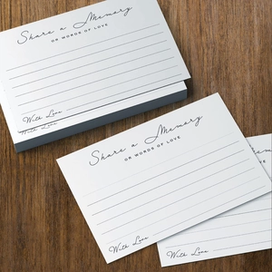 Cartes Share a Memory blanches élégantes avec lettrage doré sur fond de bois sombre