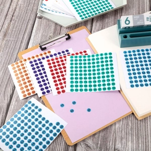 Close-up of multicolor 10mm round number stickers 1-100 on a wooden office desk
