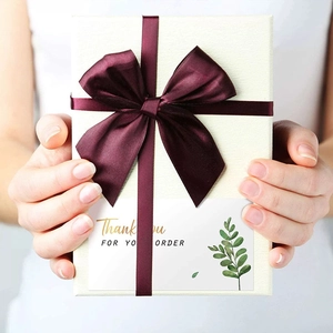 Elegante Geschenkbox mit lila Seidenband und Dankeskarte mit Eukalyptus-Zweig