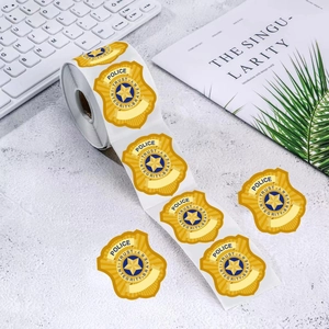Roll of yellow police badge stickers with blue star, trust and bravery text on grey desk