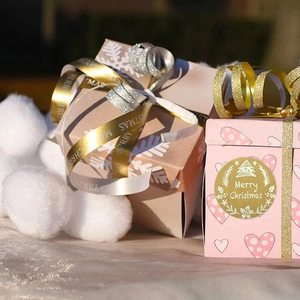 Close-up of Merry Christmas stickers on kraft paper gift boxes with glitter ribbons