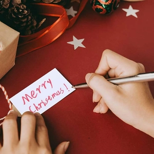 Silberner Metall-Geschenkstift schreibt Weihnachtsgrüße auf festliche Weihnachtskarten