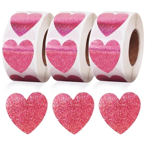 Detail of pink holographic heart stickers on rolls and loose for DIY crafts