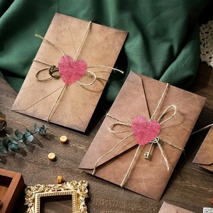 Detail of vintage kraft envelope with pink glitter heart sticker and key charm