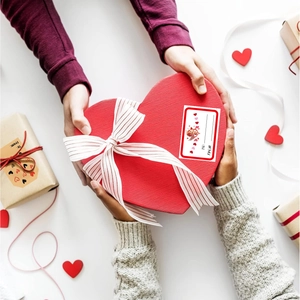 Quadratische Valentinstag-Aufkleber auf einer roten Herz-Geschenkbox mit weißer Schleife