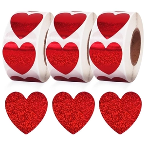 Macro view of red glitter heart-shaped stickers on rolls for Valentine gift wrapping