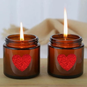 Close-up of holographic red glitter heart stickers on warm glass candle jars for decor