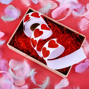 Holographic red heart stickers roll in gift box with festive decorative feathers