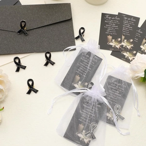 Funeral remembrance set with black enamel ribbon pin, organza bag, and memorial card