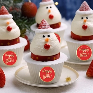 Close-up of Happy New Year stickers on snowman cupcakes with strawberry hats and red polka dots