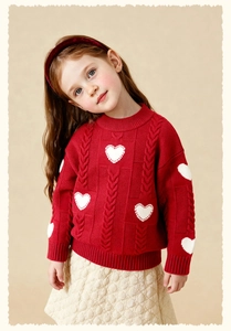 Girl's festive red knit sweater featuring white heart patterns and chunky cable knit texture