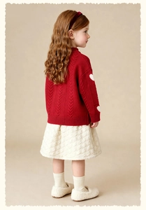 Detail of red cable knit girls sweater with heart pattern and quilted skirt outfit