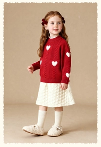 Detail of red cable-knit heart sweater and white quilted skirt for girls' winter outfit
