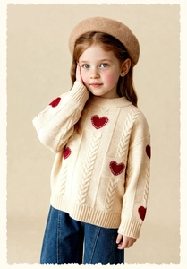 Close-up of cream cable-knit sweater with red heart pattern and wide-leg denim jeans