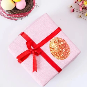 Detail of glittery orange Easter egg sticker with golden hearts on a pink gift box