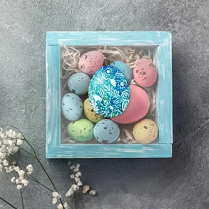 Colorful glitter Easter egg set with floral patterns on a blue tray for holiday decoration