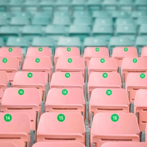 Detail of pink stadium seats with green number stickers from 13 to 17 on backrests