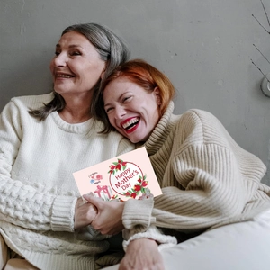 Close-up of a mother and daughter hugging while holding a Happy Mother's Day card