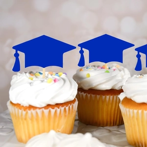 Navy blue graduation cap cupcake toppers with tassels on white frosted cupcakes