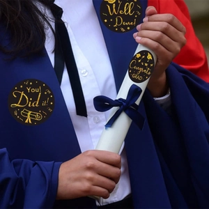 Black and gold graduation stickers with Congrats Grad text on a student in blue gown