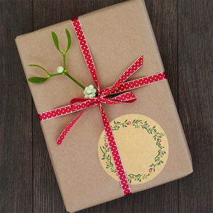 Detail of round kraft paper seal sticker with green floral wreath on gift box packaging