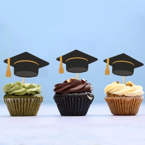 Graduation cap cake toppers with yellow tassels on cupcakes over blue background