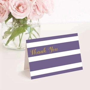 Purple striped Thank You card with gold lettering and envelope on a desk with flowers