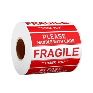 Roll of red and white Fragile Handle With Care shipping labels on plain white background