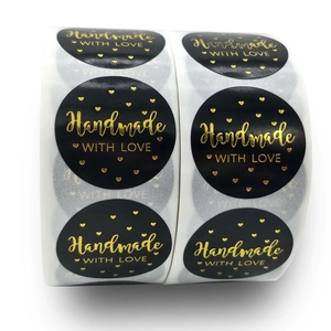 Κοντινό πλάνο χρυσού κειμένου Handmade WITH LOVE σε μαύρες στρογγυλές ετικέτες