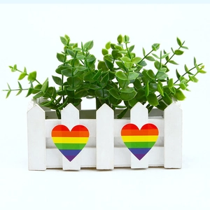 Close-up of white decorative picket fence planter with green plants and rainbow hearts