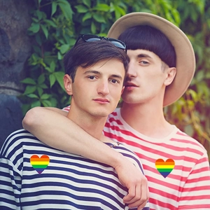 Matching couple wearing navy and red striped cotton T-shirts with rainbow heart patches