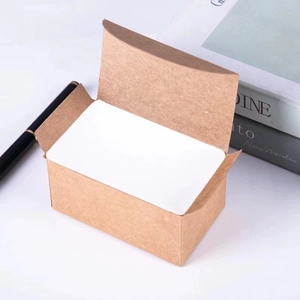 Close-up of blank white DIY cards in kraft paper box with pen and magazine props