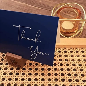 Navy blue Thank You card with wooden base holder on rustic background for office or home