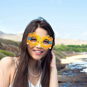 Cheerful yellow sun-shaped party glasses with blue flowers and white gloves on the beach