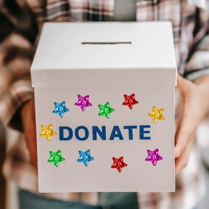 Close-up of holographic star stickers on a white donation box held by hand
