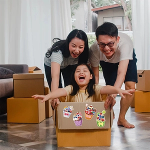 Cartoon cupcake stickers for DIY crafts on a cardboard box in a warm home setting