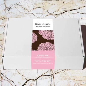 White rectangular gift box with floral 'OPEN ME' paper sleeve on marble background
