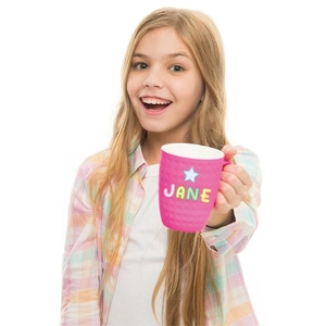 Child holding personalized pink mug with JANE letter stickers and star decoration