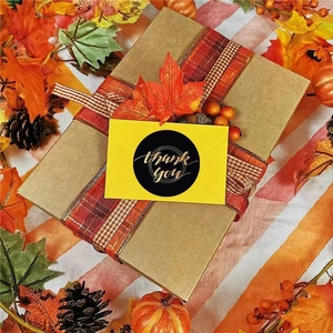 Black round Thank You stickers with gold lettering on craft gift boxes with autumn decor
