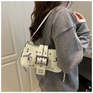 Detail of off-white punk shoulder bag with metallic rivets and decorative zippers