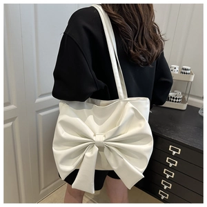 Dettaglio della borsa tote bianco crema con fiocco grande indossata a spalla