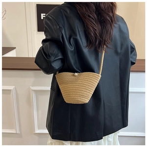 Detail of hand-woven straw bucket bag with large pearl closure on female model