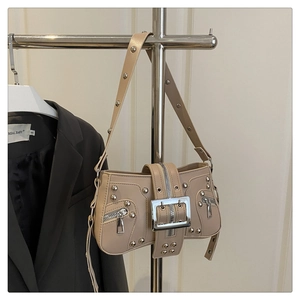 Close-up of beige biker shoulder bag with silver rivets and large metal buckle detail