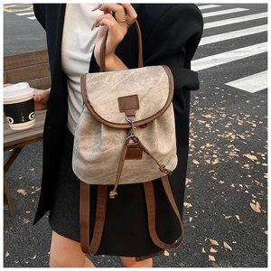 Detail of vintage canvas backpack featuring faux leather trim and metallic buckle closure